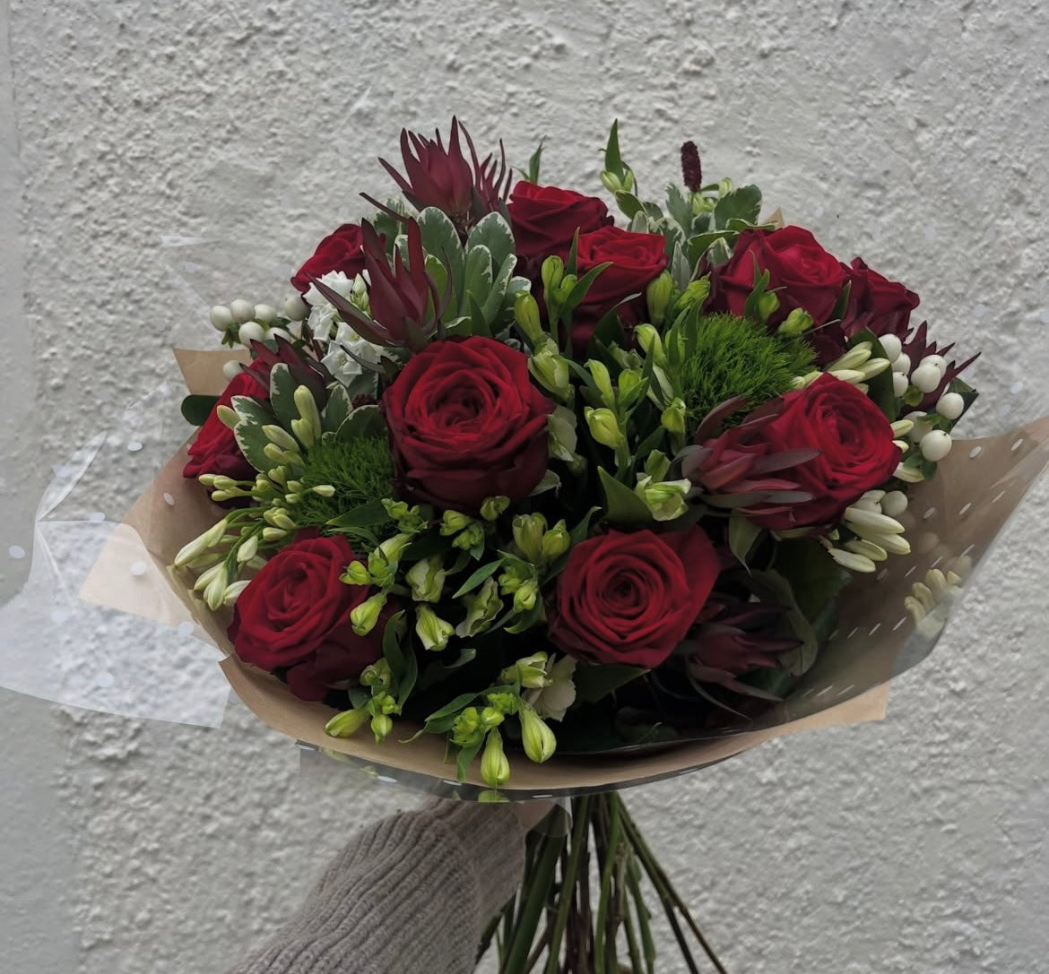 Cupid bouquet — deep red roses, white freesia, green chrysanthemums and hypericum berries wrapped in kraft paper