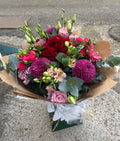 The Velvet Bouquet — crimson carnations, purple pompom chrysanthemums, pink spray roses and eucalyptus wrapped in kraft paper